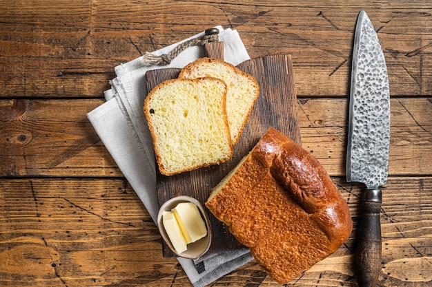 Baked sliced Brioche bread with butter Wooden background Top view