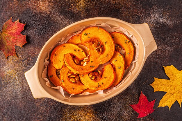 Baked slices of pumpkin on a dark surface with leaves