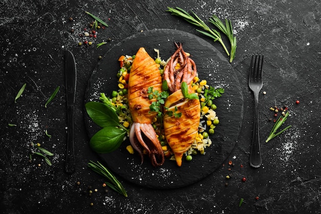 Baked squid with rice and vegetables on a black stone plate Seafood Top view Free copy space