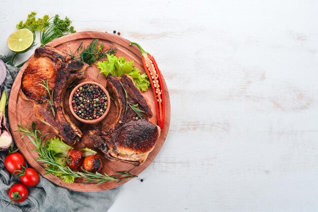 Baked steak on the bone with spices and vegetables On a wooden background Top view Copy space