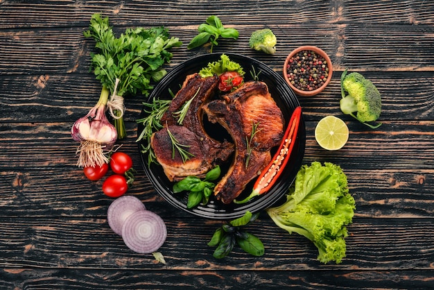 Baked steak on the bone with spices and vegetables On a wooden background Top view Copy space