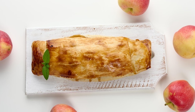 Baked strudel with apples on a white wooden board delicious dessert