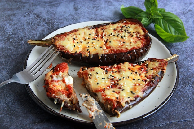 Baked stuffed eggplant with mozzarella cheese and tomato sauce on the plate at the grey background