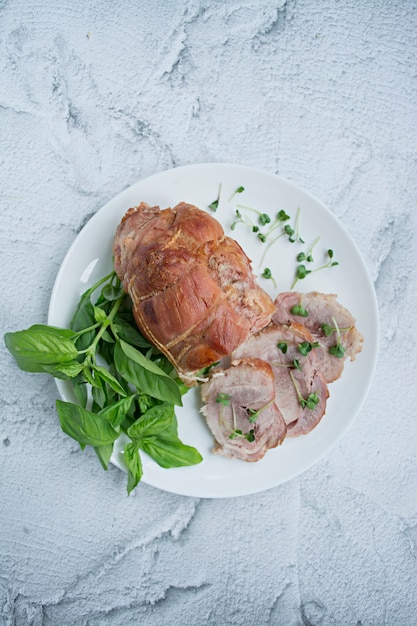 Baked stuffed meatloaf with greens served on a white plate. 