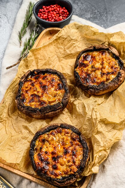 Baked stuffed mushrooms on a wooden cutting Board. Gray background. Top view.