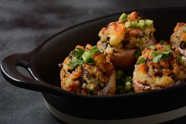 Baked stuffed potatoes with bacon, green onion,mushrooms and cheese in frying bowl