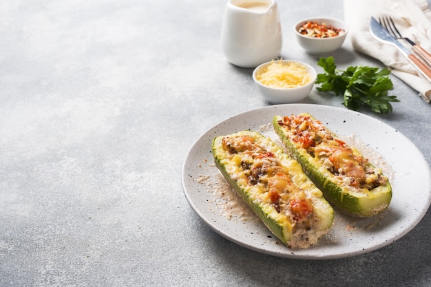 Baked stuffed zucchini boats with minced chicken mushrooms and vegetables with cheese on a plate. copyspace