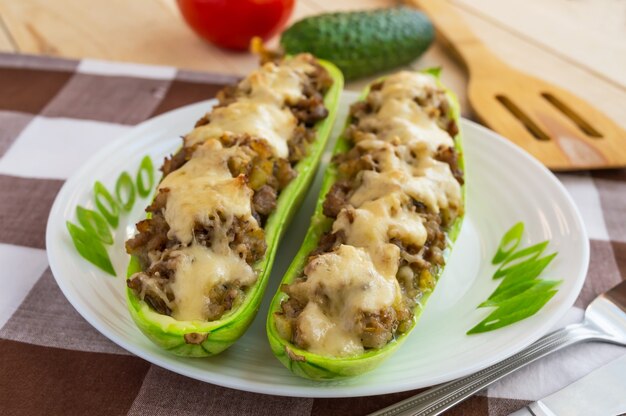 Baked stuffed zucchini, and vegetables on a white plate close up. Dietary lunch.