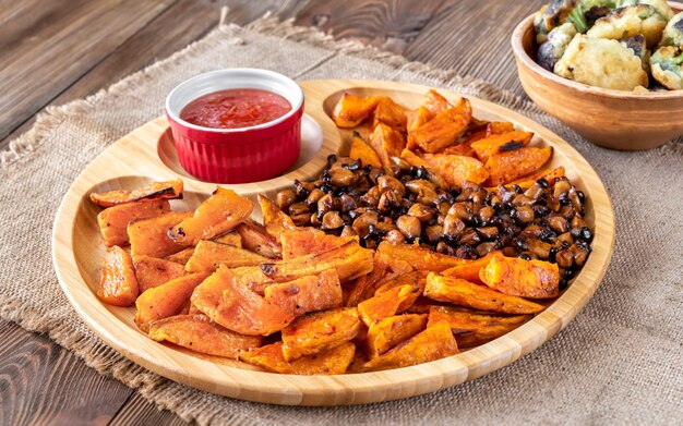 Baked sweet potato with fried mushrooms on the wooden tray