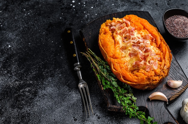 Igname di patate dolci al forno ripieno di carne macinata e formaggio. sfondo nero. vista dall'alto. copia spazio.