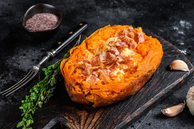 Baked sweet potato yam stuffed with ground beef and cheese. Black background. Top view.