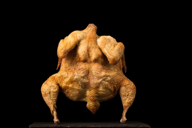 Baked tobacco chicken with spices on a black background