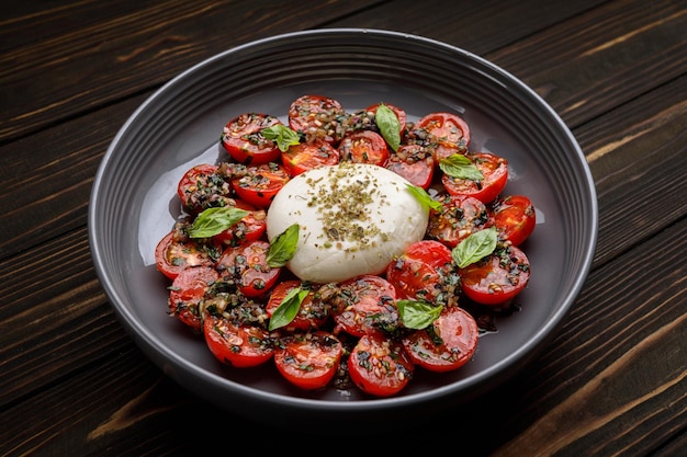 Baked tomatoes with mozzarella cheese on a wooden background