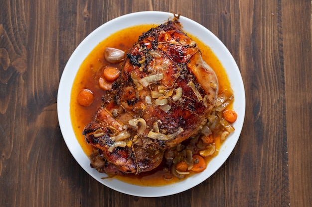 Baked turkey leg with vegetables and herbs on white dish