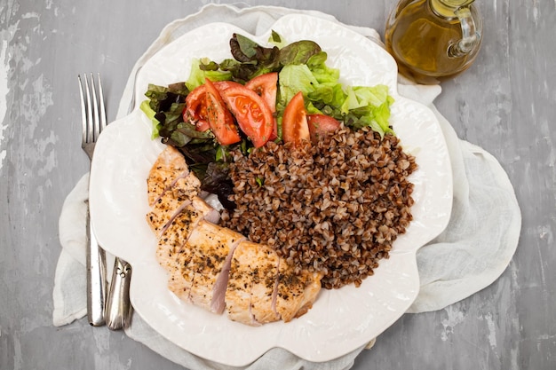 Baked turkey with buckwheat and vegetable fresh salad on white plate