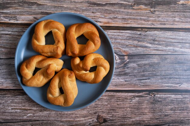 Baked twisted buns on a blue plate on a wooden background