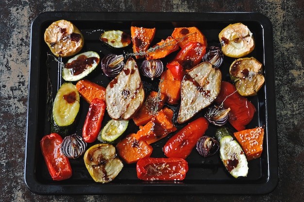 Baked vegetables and fruits on a baking sheet. Vegan theme. Appetizing baked vegetables and fruits with spices.