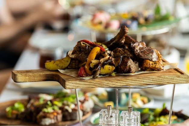 Baked vegetables with beef ribs on a wooden plate board on a served table