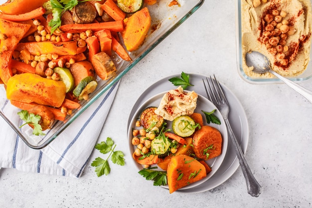 Baked vegetables with chickpeas and hummus. Flat lay vegan food.