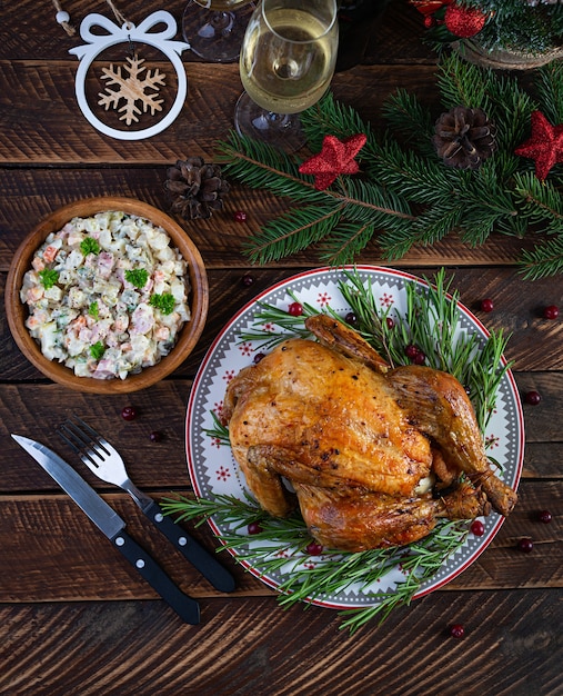 Baked whole chicken or turkey for Christmas. New Year's table with decoration, homemade roasted chicken, wine and salad. Top view