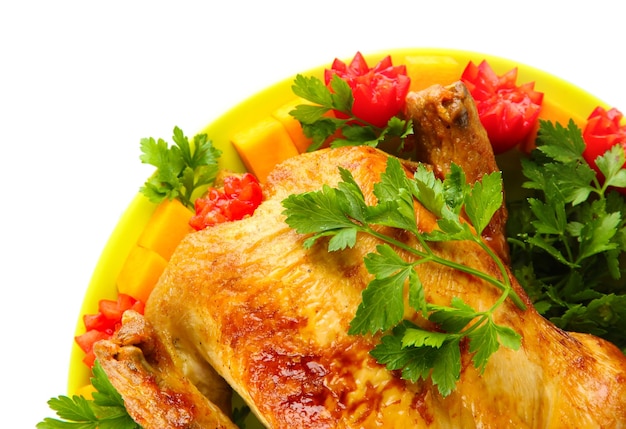 Baked whole chicken with vegetables on a green plate on white background closeup