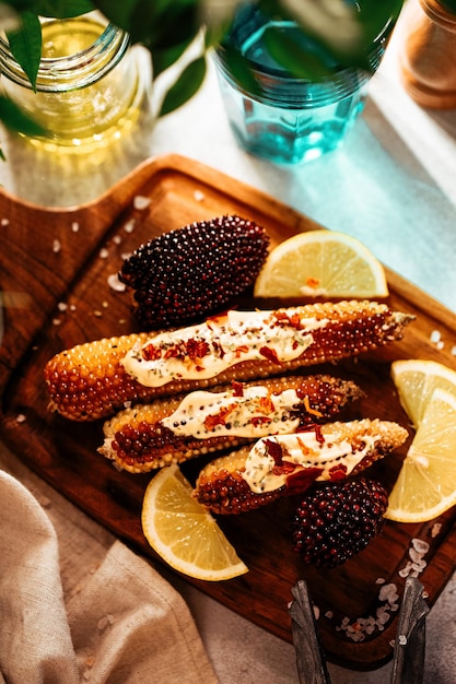 Baked whole corn with sauce and lemon vertical photo