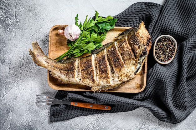 Eglefino di pesce intero al forno su un tagliere. sfondo grigio. vista dall'alto