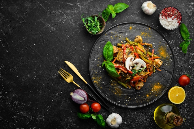 Photo baked wok vegetables on a black stone plate asian cuisine top view