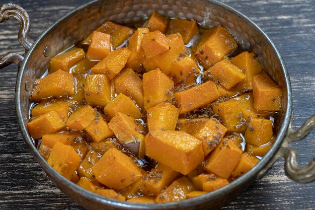 Baked yellow pumpkin with honey anise olive oil and spices on a plate on the wooden table Vegetarian food Close up