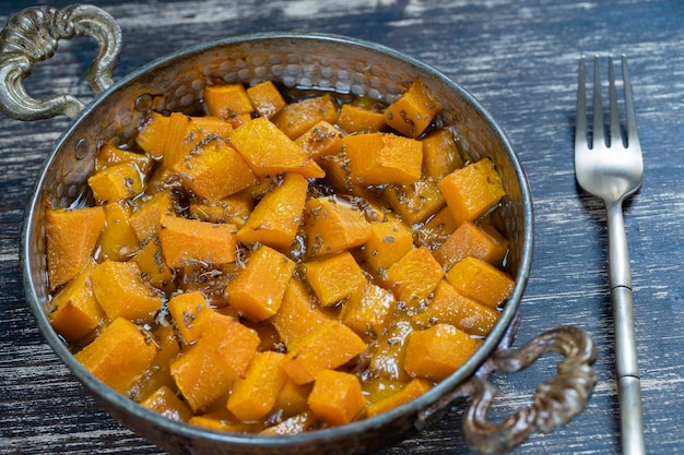 Baked yellow pumpkin with honey anise olive oil and spices on a plate on the wooden table Vegetarian food Closeup