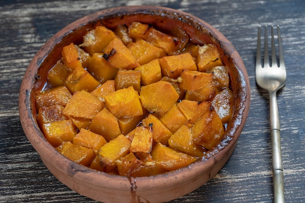 Baked yellow pumpkin with honey, olive oil and spices on a plate on the wooden table. Vegetarian food. Close up