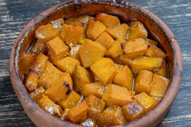 Baked yellow pumpkin with honey olive oil and spices on a plate on the wooden table Vegetarian food Closeup