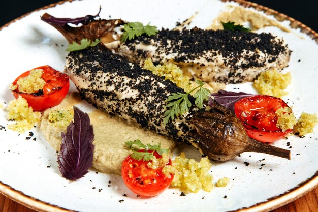 Baked zucchini with hummus and grilled tomato in a white plate