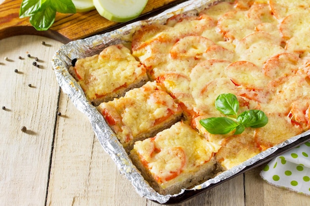 Foto zucchine al forno con carne di riso pomodori e formaggio su un tavolo da cucina in legno