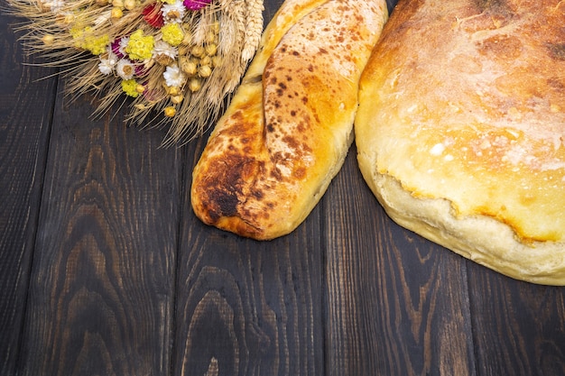 Bakeds loafs of Ukrainian national bread and a bouquet of dried flowers on black table