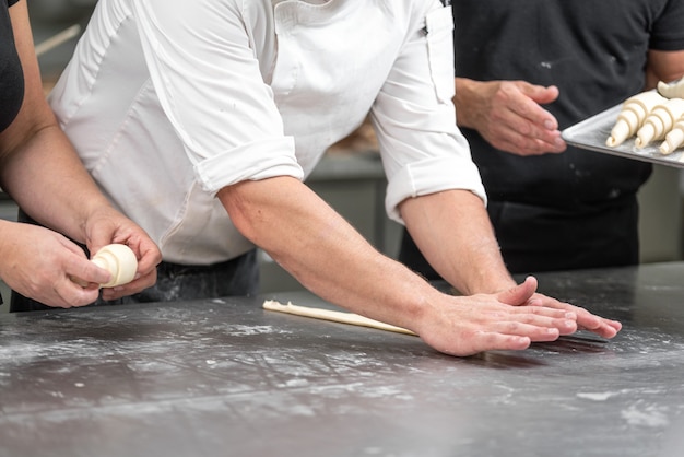 Foto concetto di baker. prepara un cornetto sul tavolo, una pasticceria fresca.