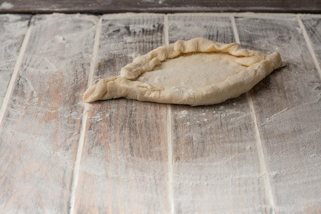 Foto baker cucina khachapuri sul tavolo della cucina una vista dall'alto del cuoco che prepara la cucina tradizionale georgiana concetto di ricetta di cucina