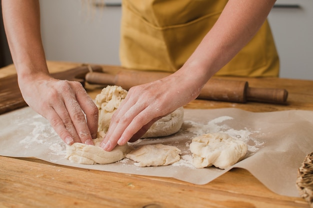 パン職人または料理の専門家が生地から製品を彫刻します。閉じる。