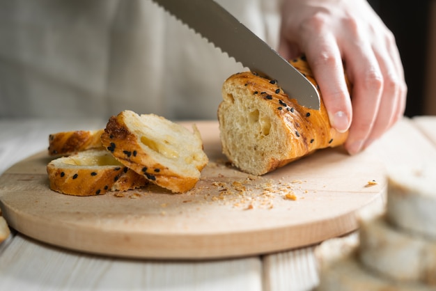 Baker cuts fresh bread into thin slices