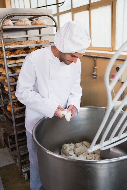 Baker die deeg in industriële mixer voorbereiden