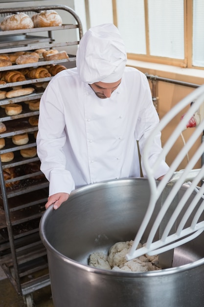 Baker die deeg in industriële mixer voorbereiden