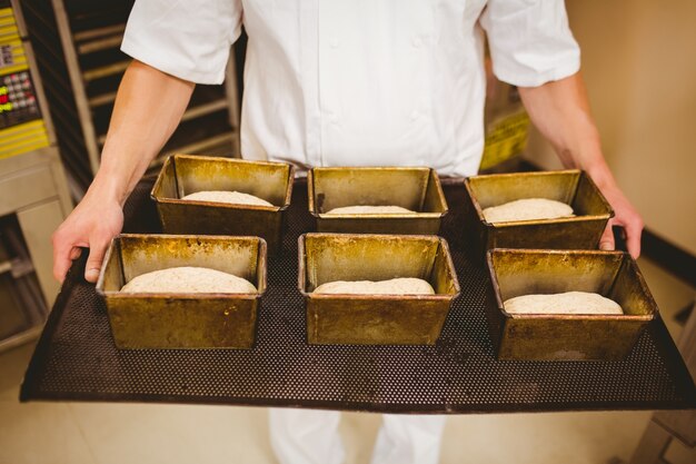 Foto baker die dienblad van broodvormen houden