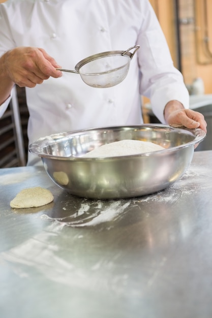 Baker die met zeef en kom werken