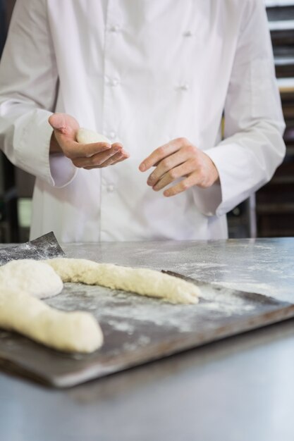 Baker die ongekookt deeg op dienblad maken