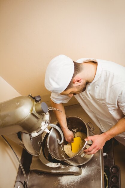 Baker gebruikt grote mixer om deeg in een commerciële keuken te mengen