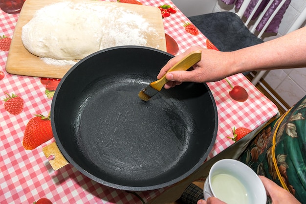 The baker greases the frying pan with butter for baking Easter cakes