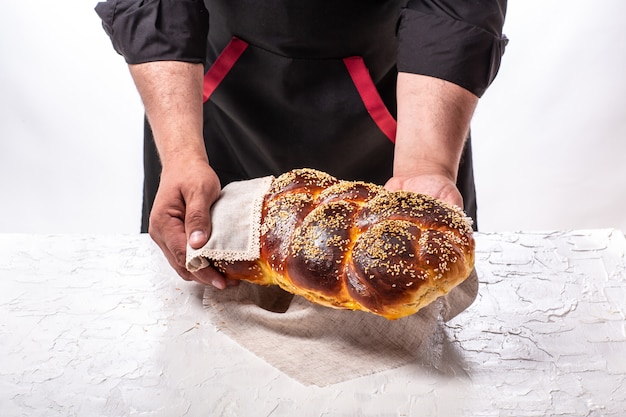 Panettiere che tiene pane ebreo challah al forno fresco