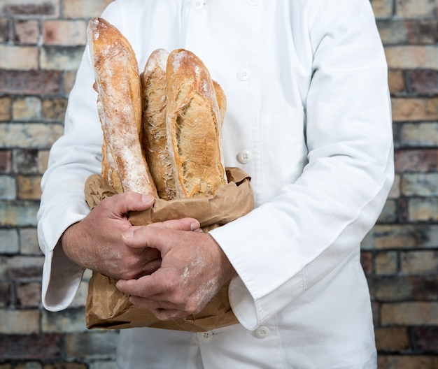 Baker holding traditional bread french baguettes