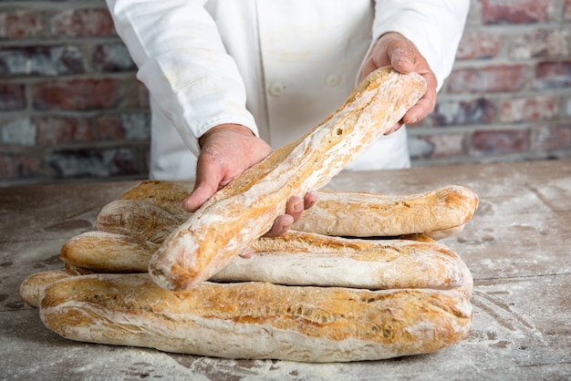 Panettiere che tiene le baguette francesi tradizionali del pane