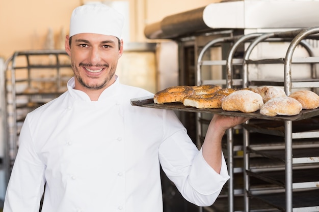 Baker holding tray of bread